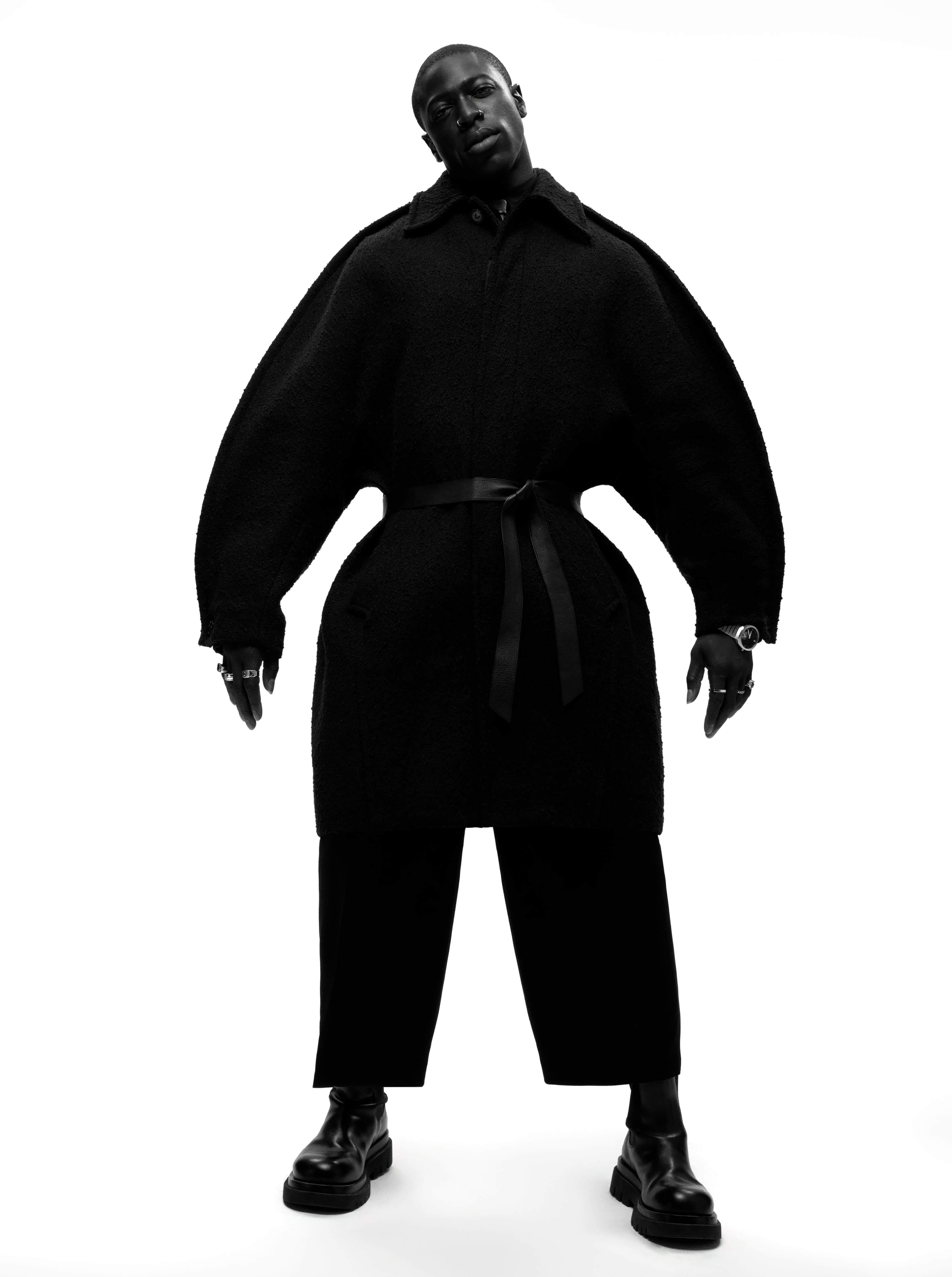 COAT, PANTS, and SHOES by ,Bottega Veneta,. SHIRT by ,Louis Vuitton,. TIE by ,Jil Sander,. BELT by ,Patricia Von Musulin,. WATCH by ,H. Moser & Cie,. RINGS by ,HOWL, and ,Miansai,, and Sumney’s own.